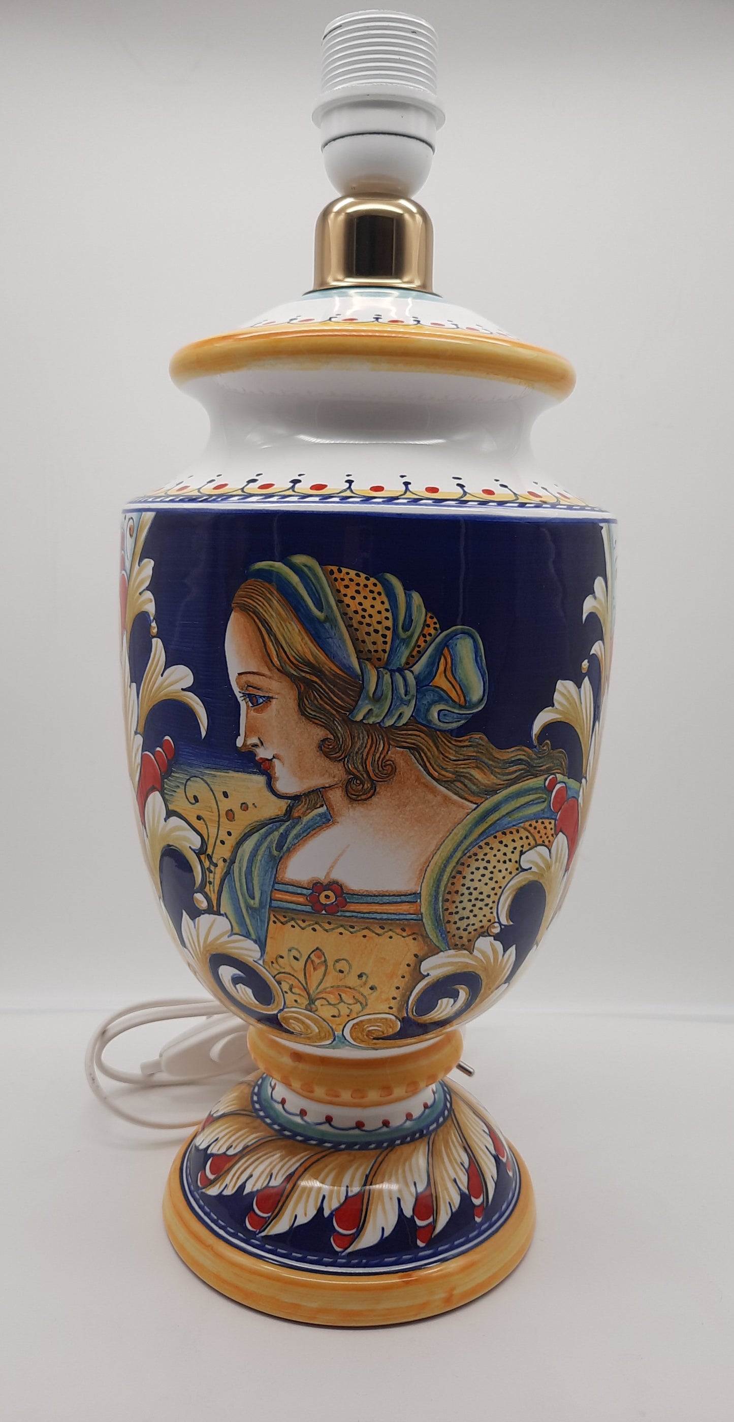 Lampada cm 35 (con cappello incluso) in ceramica dipinta a mano raffigurante Donna Rinascimentale. Colori e immagini sono quelli tradizionali derutesi, un vero e proprio pezzo classico.