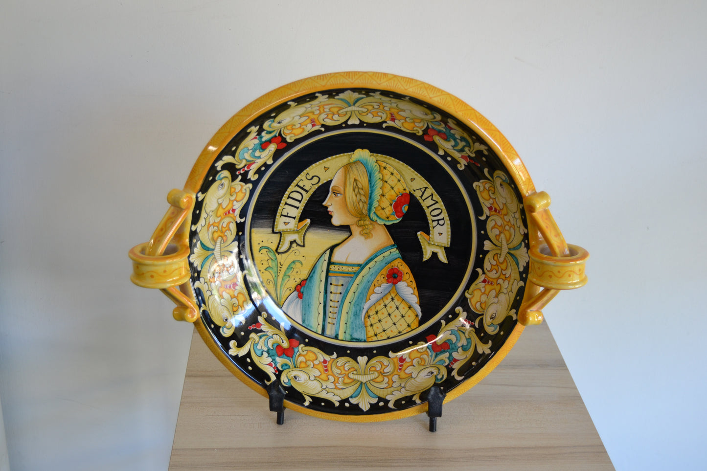 Centrotavola con manici dipinto a mano in ceramica tornito a mano cm 42. Un pezzo classico della tradizione derutese. Al centro figura femminile Rinascimentale e con bordo Delfini